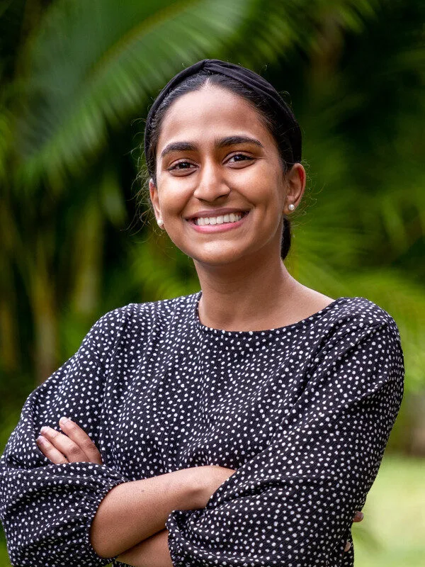 Smiling person in polka dot shirt, green background.
